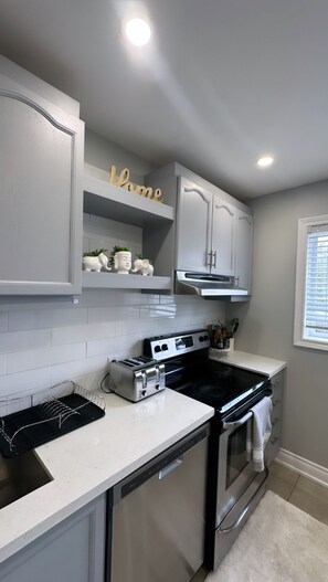 A kitchen with white cabinets, a built-in oven, a toaster, and a 'Home' sign above the cabinets. - 
Clifton Hill/  Niagara Falls , Pet (Niagara Falls)