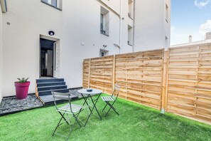 A small outdoor area with a wooden fence, a table with chairs, and a potted plant. - 2P Studio With Patio Near Paris (Le Pre-Saint-Gervais)