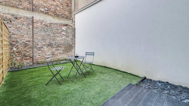A small outdoor area with artificial grass, two chairs, a table, and a brick wall. - 2P Studio With Patio Near Paris (Le Pre-Saint-Gervais)