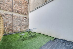 A small outdoor area with artificial grass, two chairs, a table, and a brick wall. - 2P Studio With Patio Near Paris (Le Pre-Saint-Gervais)