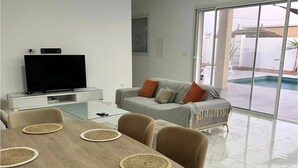 Een moderne woonkamer met een eettafel, stoelen, een bank en een televisie.