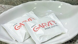 Una ciotola bianca contenente due bustine bianche con la scritta 'GARVEY PARK HOTEL'.