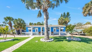 Un bâtiment bleu doté d’une cour intérieure, entouré de palmiers et d’une pelouse bien entretenue.