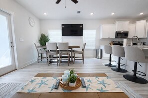 A modern kitchen with white cabinets, a microwave, and a sink.