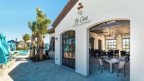Eine Bar und ein Lounge-Bereich mit Außenplätzen und einem Pool im Hintergrund.