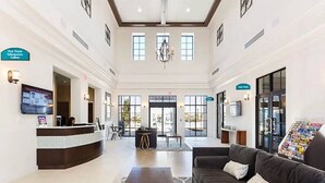Eine geräumige Lobby mit einer Rezeption, einer Couch, einem Couchtisch und einem Chandelier.