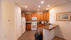 A kitchen with wooden cabinets, a white refrigerator, a stove, a microwave, and a sink. - Mountain View Retreat Near Downtown AVL! (Asheville)