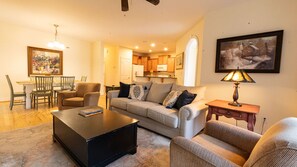 A living room with a sofa, coffee table, and chairs, a dining area with a table and chairs, and a kitchen in the background. - Mountain View Retreat Near Downtown AVL! (Asheville)