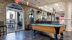 A pool table in a room with a stone wall, an exit sign, and a bar area. - 4Bd 3Ba, (2 Primary), 8.7m to Disney, No Resort Fees! (Davenport)