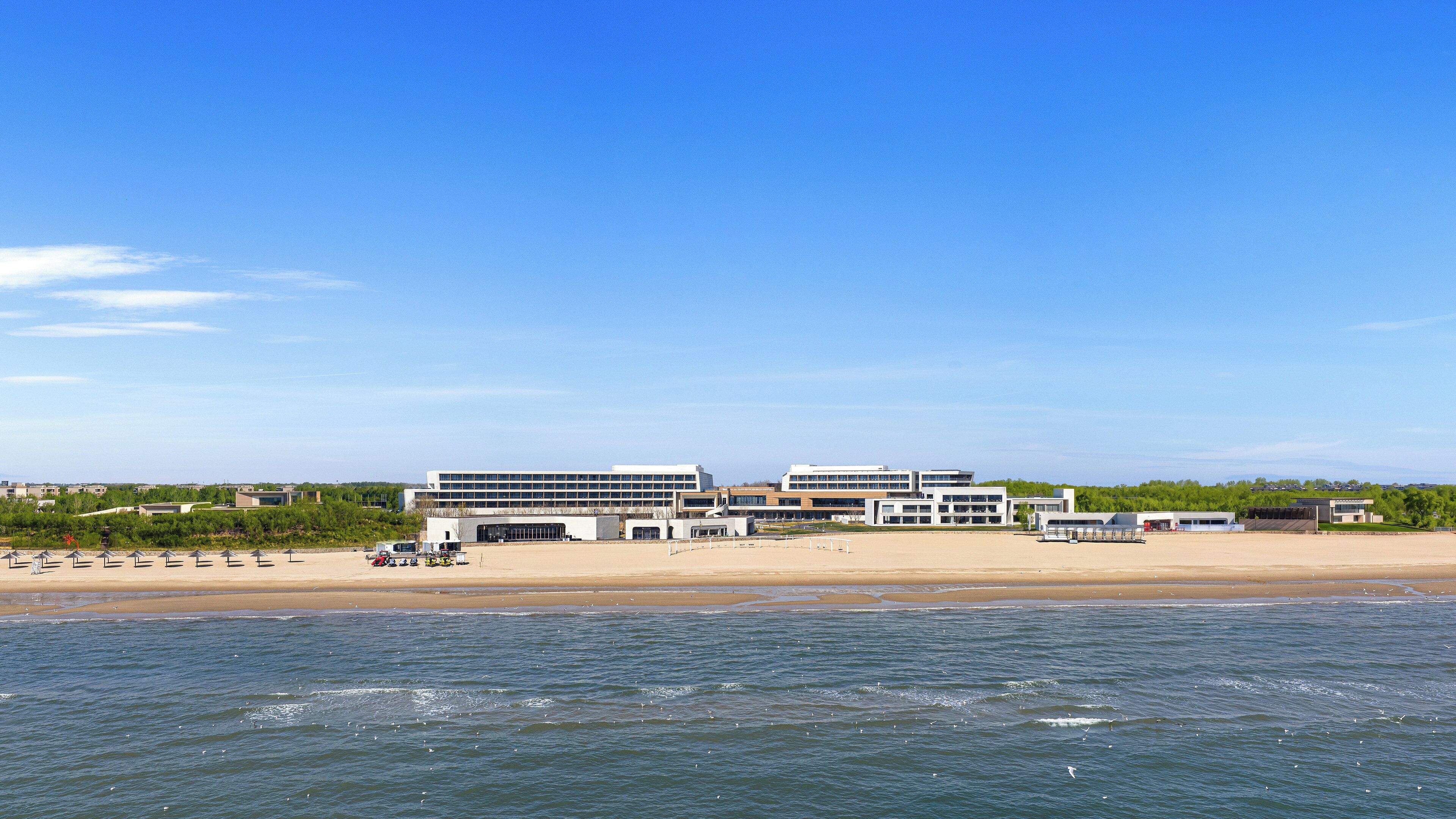 Un hotel costero de arquitectura moderna, una playa y vista al mar.