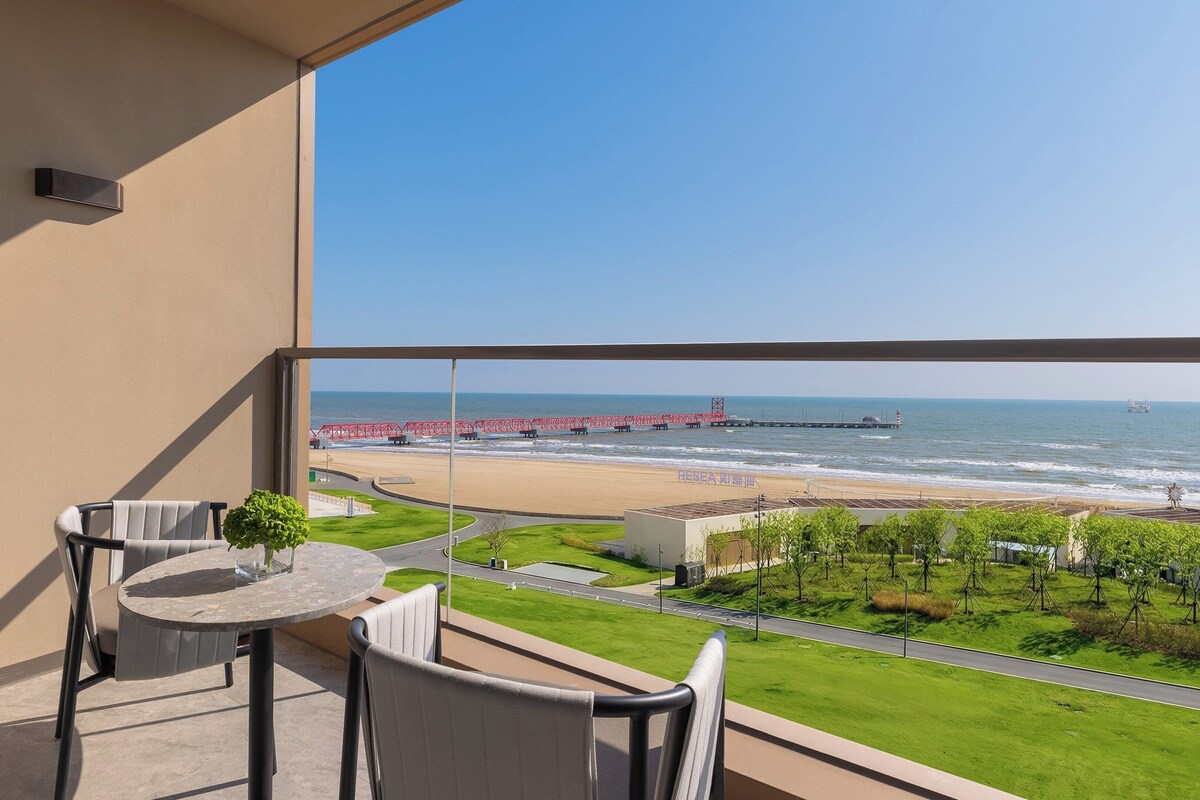 Un balcon avec vue sur la plage, un pont rouge et un phare.