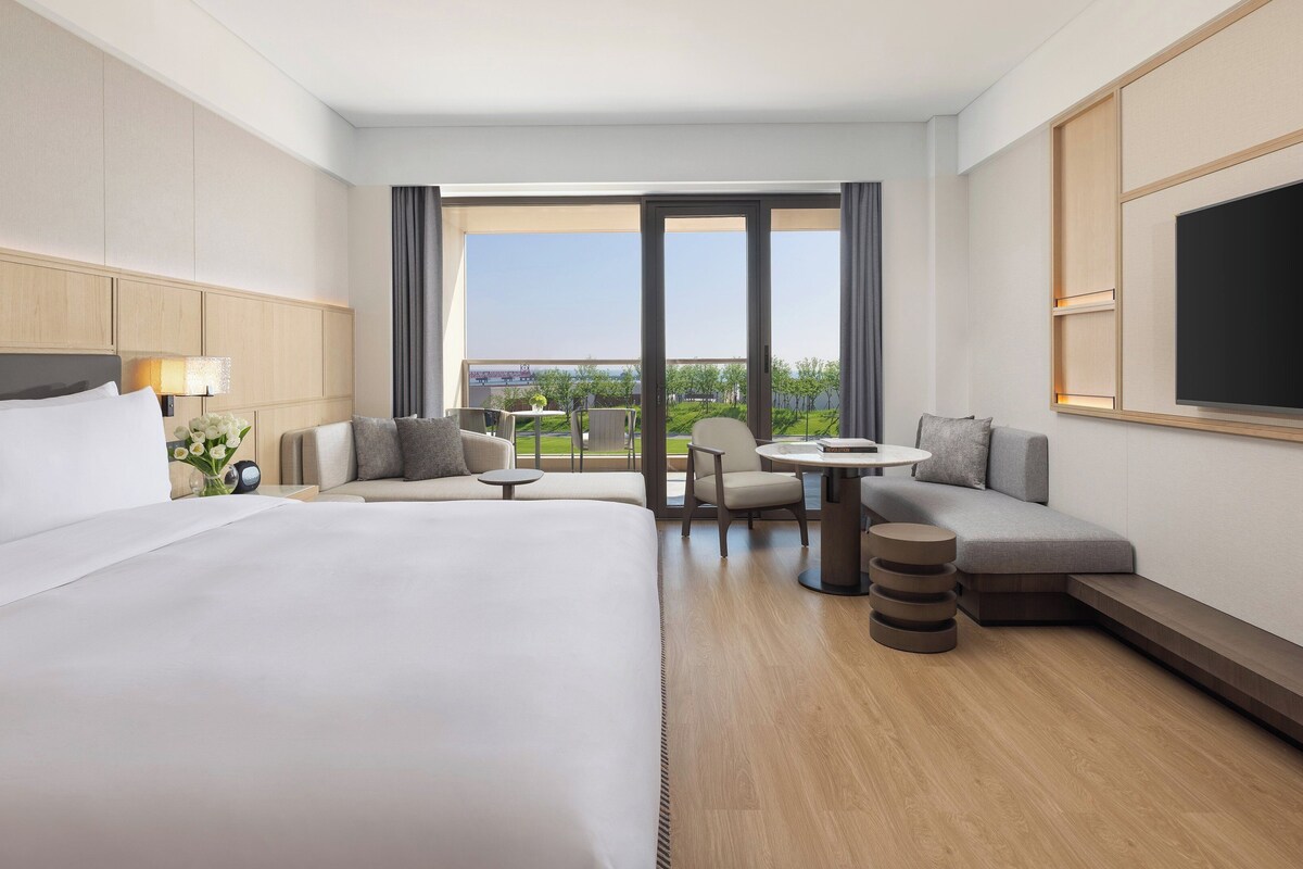 Une chambre d’hôtel avec un grand lit, un canapé, une petite table et un téléviseur.