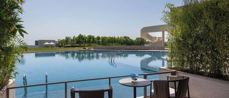 A swimming pool with a modern design, surrounded by greenery and a clear sky.
