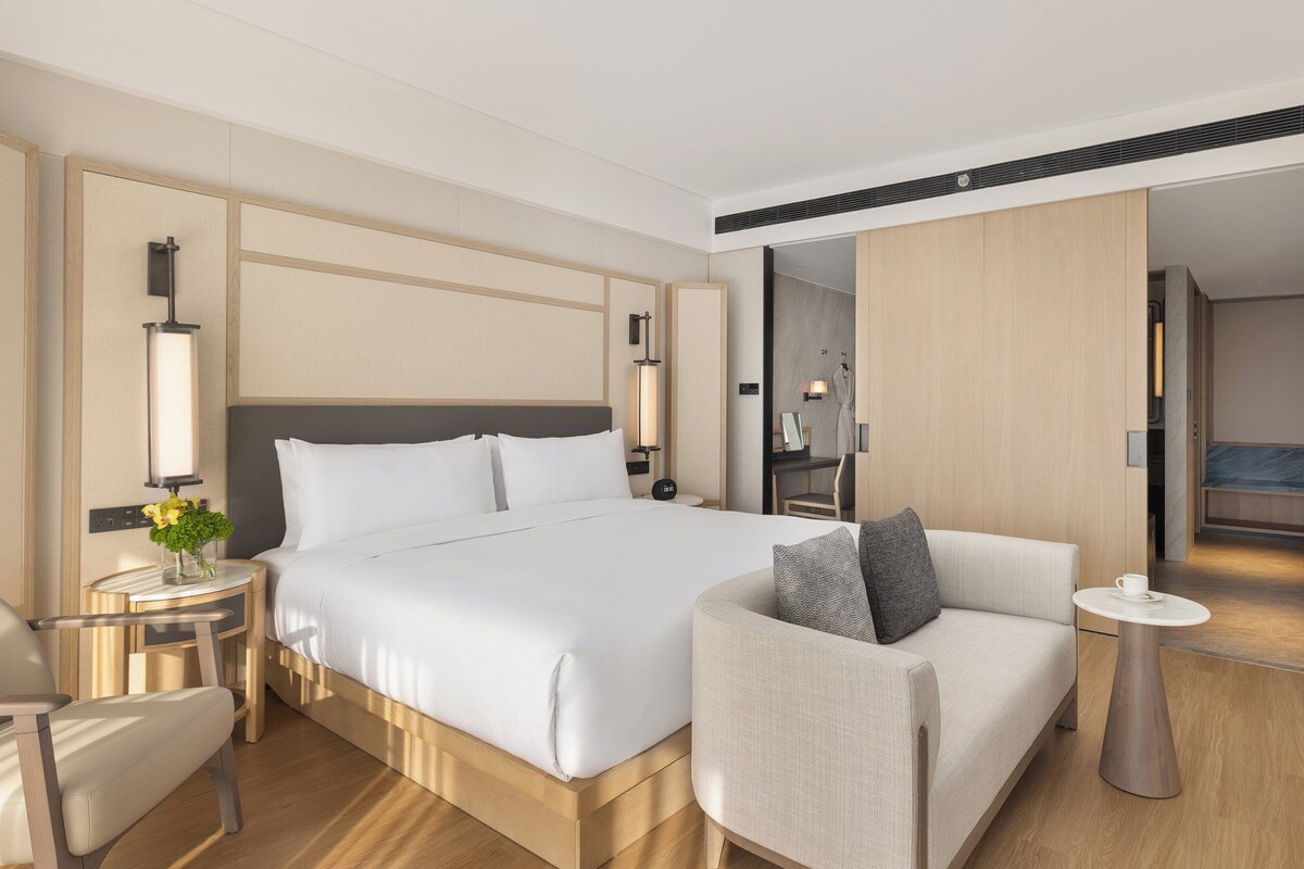 Une chambre d’hôtel moderne avec un grand lit, un coin salon, une petite table et un téléviseur.