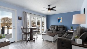 A living room with a ceiling fan, a dining area with a table and chairs, and a sofa.