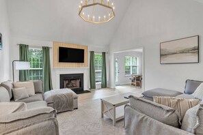 Una sala de estar amplia con chimenea, un televisor de pantalla plana y un comedor.