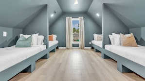 Habitació amb dos llits, ventilador de sostre i finestra amb cortines.