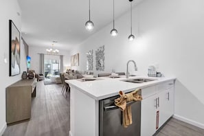 A modern kitchen with a central island, a dining area, and a living space. - The Majestic retreat by Disney (Davenport)