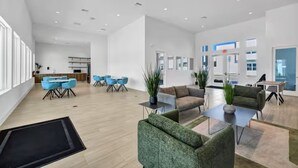 A spacious, modern hotel lobby with a dining area, seating arrangements, and a reception desk. - The Epic Retreat by Disney (Davenport)