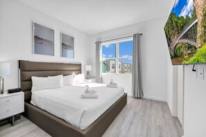 A modern hotel room with a large bed, a TV, and a window with curtains. - The Enchanted ReTreat by Disney (Davenport)