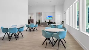 Una amplia sala de conferencias con mobiliario moderno, un televisor de pantalla plana y ventanas grandes.