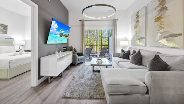 Ein modernes Wohnzimmer mit Flachbildfernseher, einer Couch, einem Couchtisch und einem Essbereich mit Stühlen.