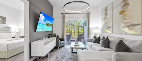 Ein modernes Wohnzimmer mit Flachbildfernseher, einer Couch, einem Couchtisch und einem Essbereich mit Stühlen.