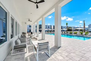 Ein überdachter Außenbereich mit Pool, Sitzgelegenheiten und Blick auf die umliegenden Gebäude.