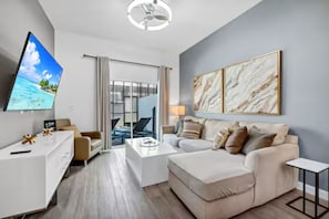 Ein modernes Hotelzimmer mit Flachbildfernseher, einer Couch, einem Couchtisch und einem Schreibtisch.