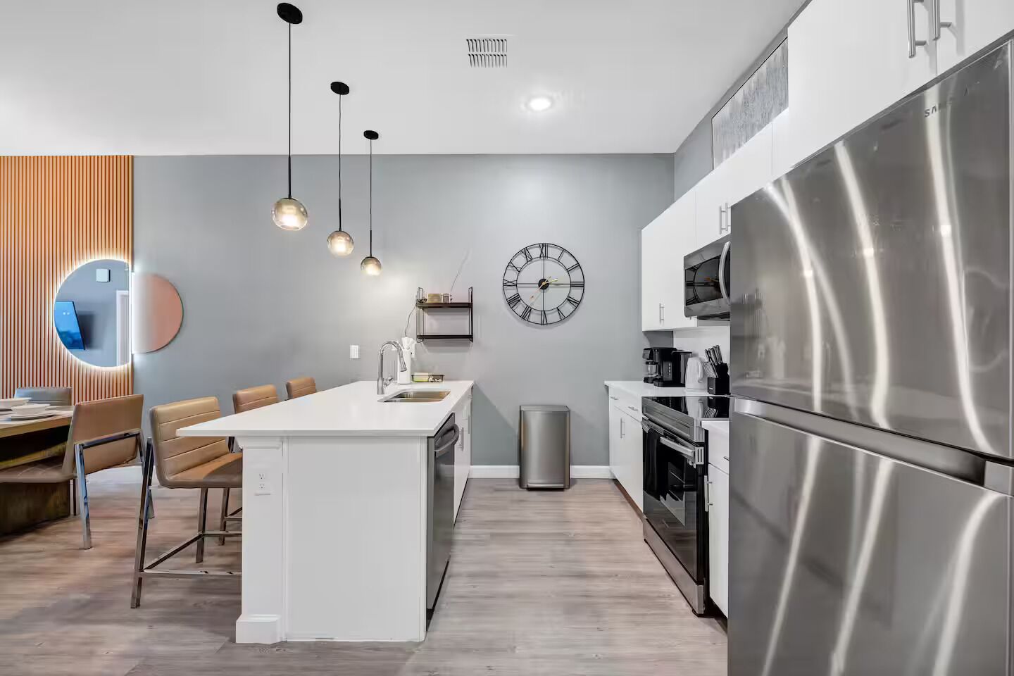 A modern kitchen with a central island, stainless steel appliances, and pendant lighting.
