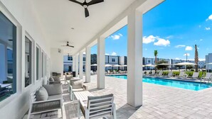 A covered outdoor area with a pool, seating, and a view of the surrounding buildings. - Serendipity @Azur Retreat by Disney w private pool (Davenport)