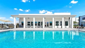 Un hotel moderno con piscina, area relax all'aperto coperta e cielo azzurro.