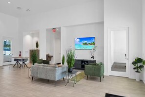 A modern hotel lobby with a sofa, chairs, a TV, and potted plants. - The Onyx Retreat by Disney / Universal/ Seaworld (Davenport)