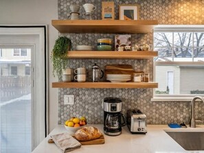 Een keuken met houten planken, een koffiezetapparaat, een broodrooster en een schaal met fruit.