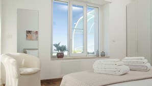 Une chambre à coucher avec un lit, une chaise, une fenêtre donnant sur un beau paysage et une plante en pot.