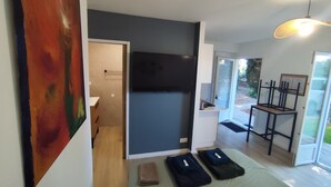 A modern bedroom with a bed, a TV, and a painting on the wall.