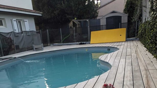 A person relaxing by a poolside with a book open in front of them.