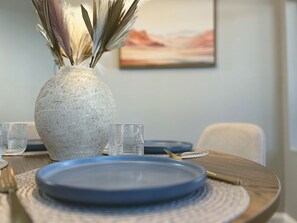 A dining table with a vase of dried plants, a clear glass, and a blue plate. - Resort Pool · Hot Tub · Great Location  · Brand New! (Scottsdale)