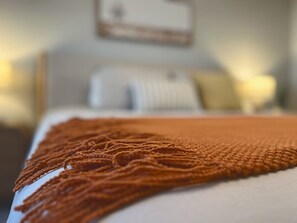 A bed with a brown knitted throw, a white pillow, and a white blanket. - Resort Pool · Hot Tub · Great Location  · Brand New! (Scottsdale)