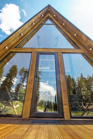A modern, triangular glass-roofed structure with a wooden deck.