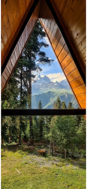 A triangular wooden ceiling with a view of a mountainous landscape through a window.