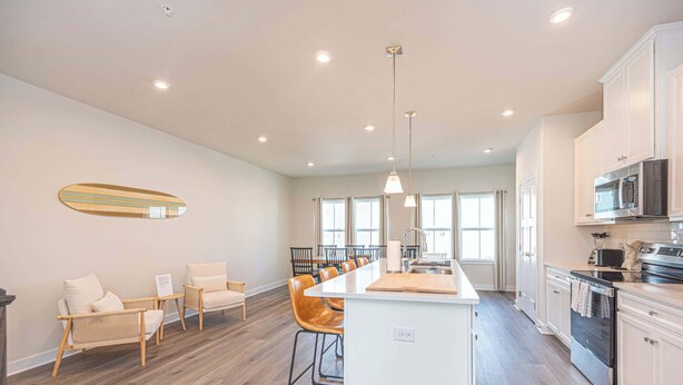 A spacious kitchen with a central island, white cabinetry, and a dining area with chairs. - Coastal Townhome with 2 Pools & Gym (Berlin)