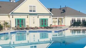 A building with a swimming pool, two green doors, and a covered patio area. - Coastal Townhome with 2 Pools & Gym (Berlin)