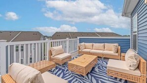 A covered outdoor patio with wicker furniture and a patterned rug. - Coastal Townhome with 2 Pools & Gym (Berlin)