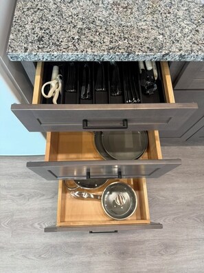 A kitchen drawer with utensils, a pot, and a pan.
