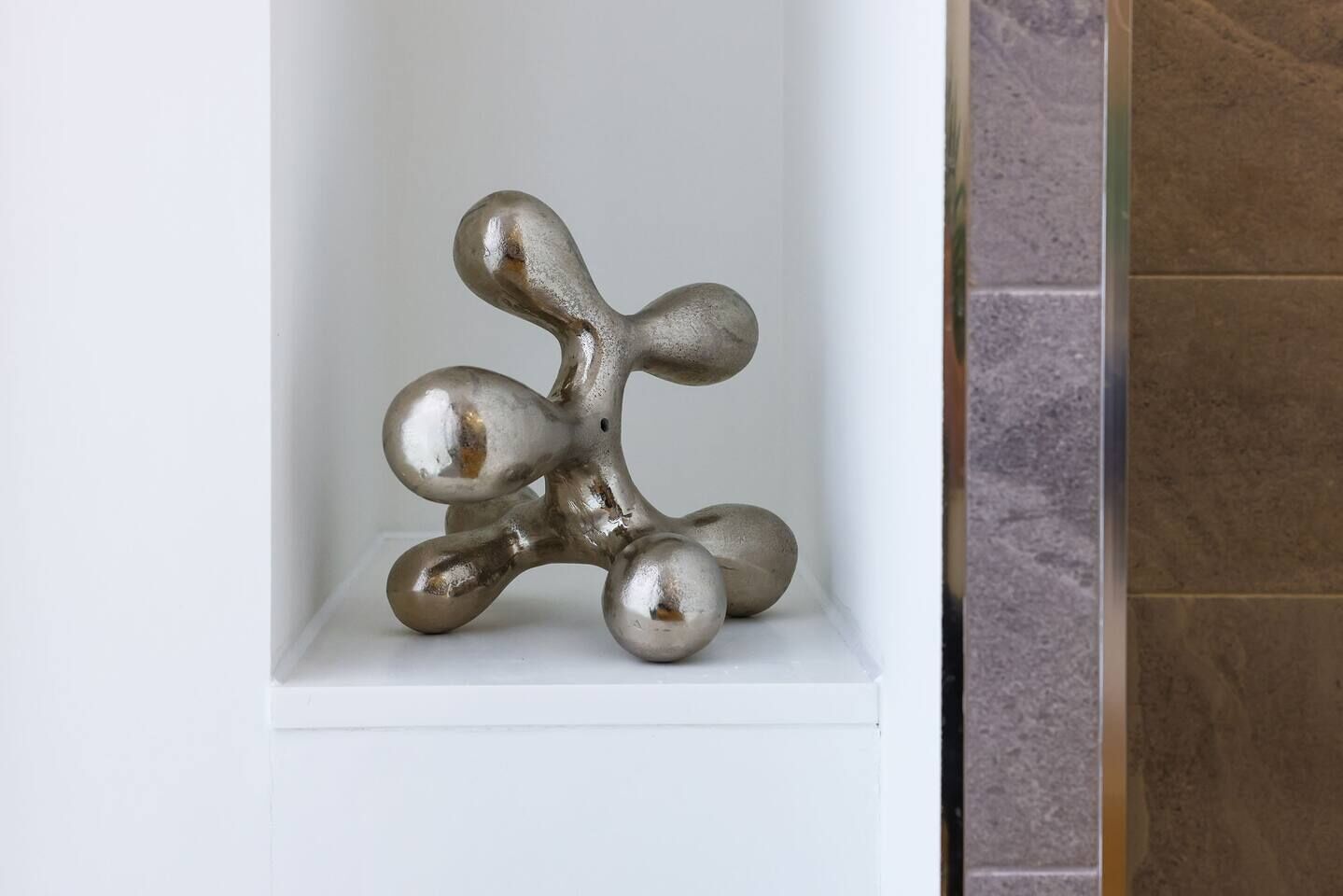 A metallic sculpture in a white alcove.