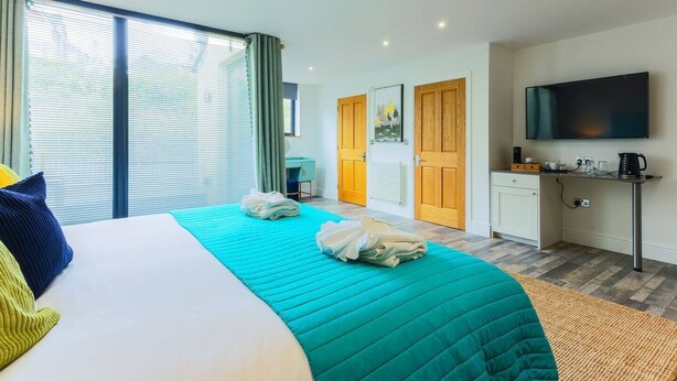 Habitación de hotel con cama, escritorio, televisor y vistas al exterior.