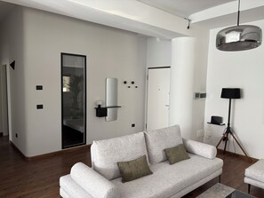 Ein modernes Wohnzimmer mit einer Couch, einer Stehlampe und einem wandmontierten Spiegel.