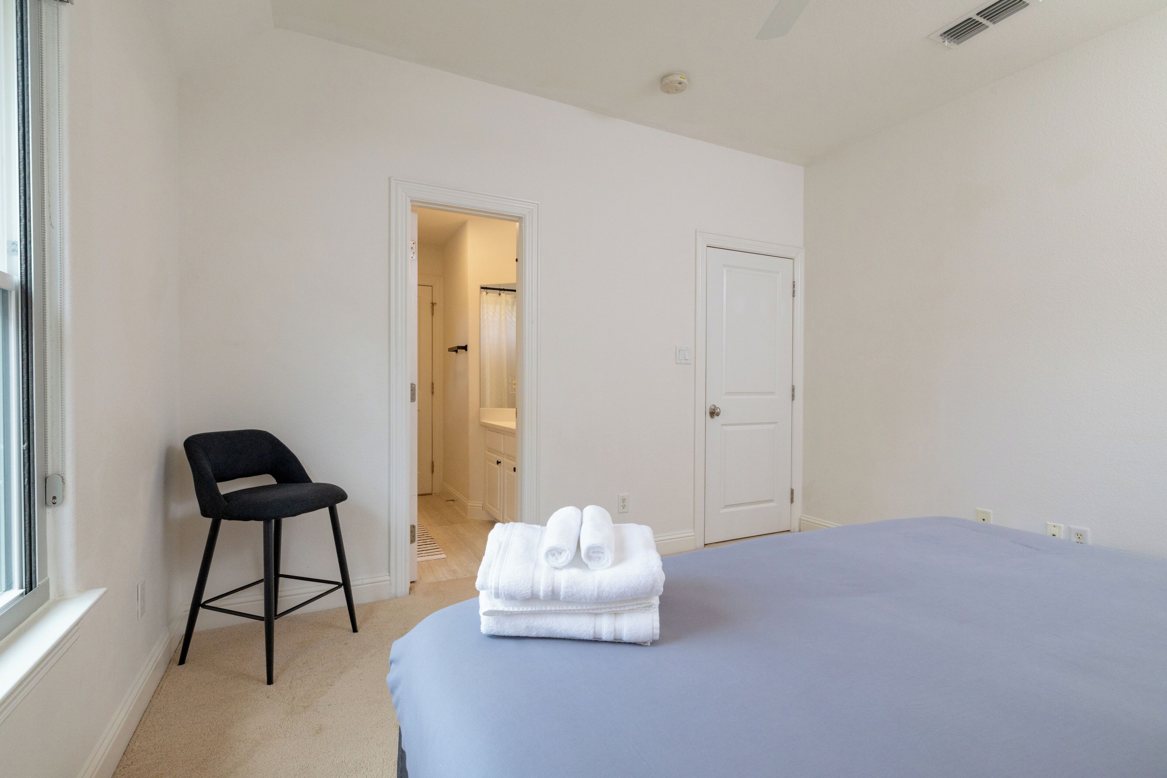 Une chambre à coucher avec un lit, une chaise, une porte et une fenêtre.