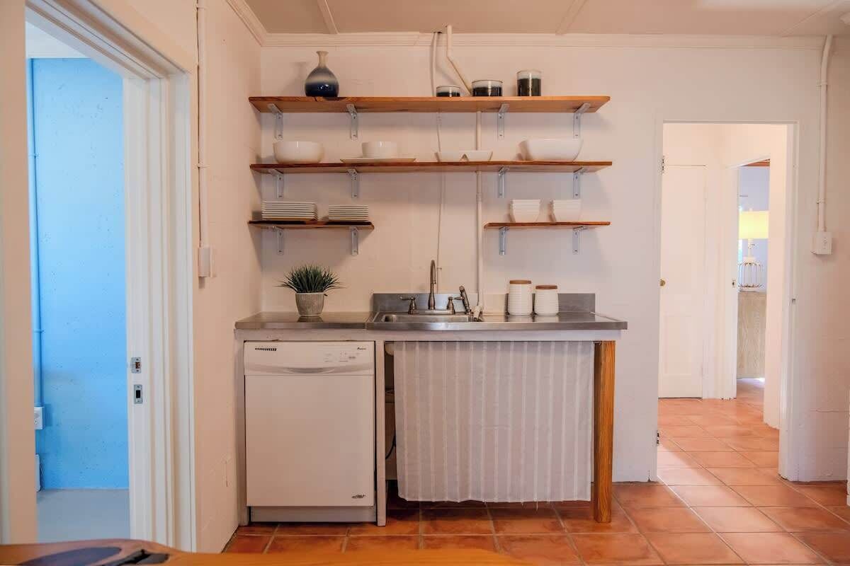 A compact kitchen with built-in shelves, a dishwasher, and a small countertop.